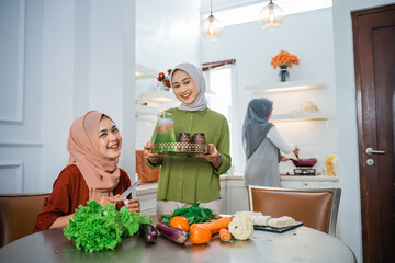 muslim woman serving drink for her friend and family at home having dinner together