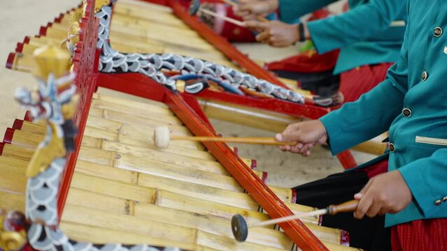 Asian musicians playing traditional bali music on ceremony in temple. Close up of man's in national balinese clothing, dress use bamboo instrument xylophone Rindik for hindu rhythm