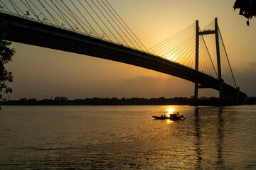 Fototapeta na wymiar Boat in the river Ganges at Kolkata It is a toll bridge over the Hooghly River in West Bengal, India, linking the cities of Kolkata and Howrah.