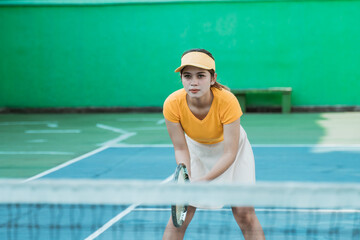 female tennis player concentrating in a position ready to receive the opponent's ball while holding...