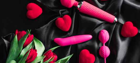 Various sex toys set on a black background. Advertising a sex shop. The view from the top. Spring. Tulips. Horizontal wide photo subtitle, cover. copy-space - obrazy, fototapety, plakaty
