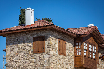 Close-up of an ancient stone building with a wooden balcony and windows