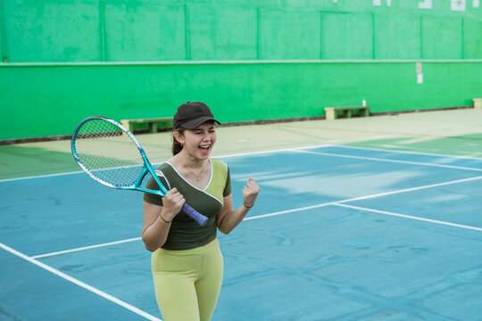 female tennis player screaming with fists clenched as she scores points while holding a tennis racket