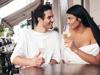 Smiling beautiful woman and her handsome boyfriend. Happy cheerful family. Sexy couple cheering with glasses of red wine at their date in restaurant. Drinking alcohol at veranda cafe