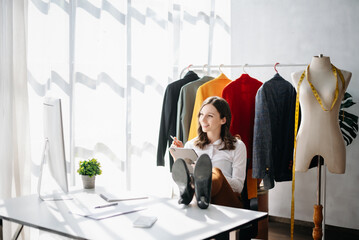 Fashion designer woman talking smart phone and using laptop with digital tablet computer in modern...