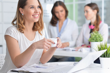 young women sit at the table and work in a modern office
