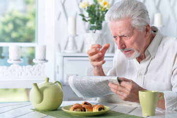 Emotional senior man reading newspaper