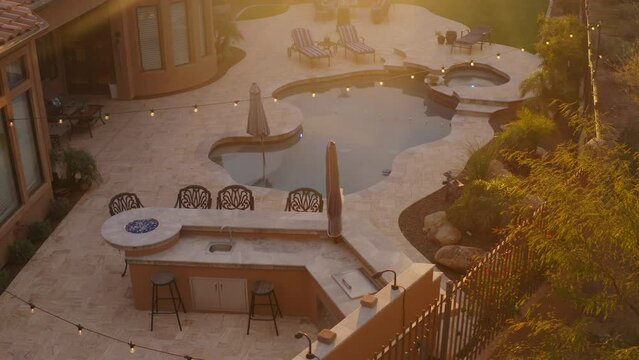 A desert landscaped backyard located in Arizona featuring
a travertine tiled pool deck outdoors kitchen and fireplace.