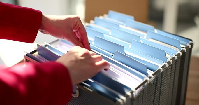 Office clerk looking for files in filing cabinet closeup