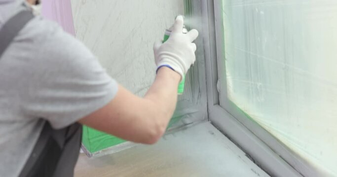 Builder paints a window layer with white spray paint