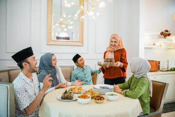 muslim woman serving drink for her friend and family at home having dinner together