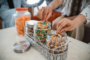 people's hands take snacks from glass tube jars full of snacks on the table in the living room