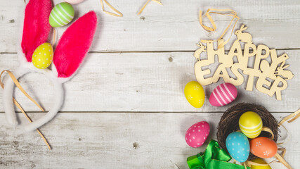 nest with colored easter eggs and rabbit ears on wooden background easter minimal flat lay top view