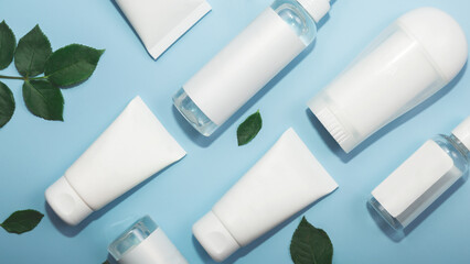 Natural organic eco-cosmetics. Beauty SPA branding mockup. Cosmetic containers with cream and lotion, serums rose leaves on blue background flat top view. Blank label for branding