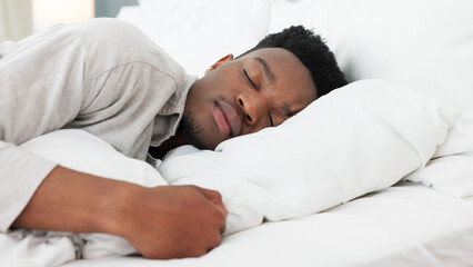 Sleep, relax and dream for a black man home in bed on a weekend morning. Tired, sleeping and dreaming in bedroom alone. Relaxing, peace and comfort with head on pillow for sleepy time in bright room.