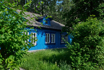 Blue wooden house of "Osiedle Przyjaźń" in Warsaw surrounded by summer greenery
