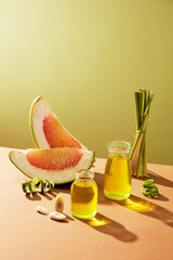 Pink pomelo (Citrus maxima) slice with glass bottle containing essential oil extracted from...