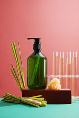 Abstract minimalist scene - empty bottle on podium, fresh lemongrass and test tube containing pink...