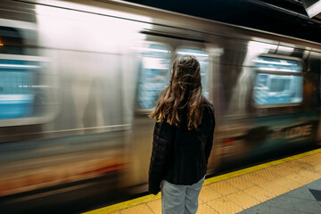 Teen girl standing in front of moving subway train