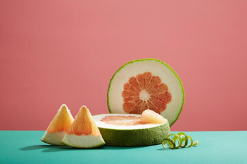 Front view of pieces fresh grapefruit on pink background. Sliced pink pomelo forms an empty podium...
