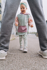 stylish baby girl in a hoodie hooligan unties dad's shoelaces
