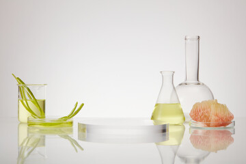 Pink pomelo peels and slices decorated with few laboratory glassware and a transparent round podium...