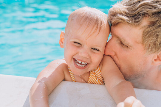 Close-up of happy father and daughter by the side of the outdoor pool