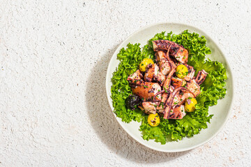 Octopus salad with lettuce, olives and spices in a bowl. Fresh and healthy seafood, marine decor
