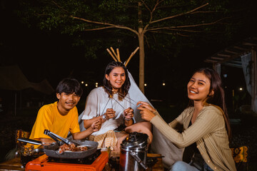 three adults playing the fireworks together while sitting in front of the tent at the camp site