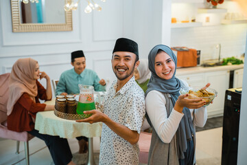 portrait of asian couple serving food for family for break fasting together during ramadan