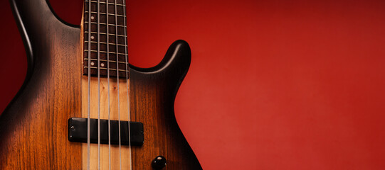 Obraz na płótnie Canvas Close up on 5 strings bass guitar with natural finish, isolated on red background