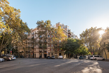 View of front entrance of a six-storey luxury building in the center of a European city on sunny warm autumn day next to a cozy urban area with parking lots. Concept of a quiet prosperous area