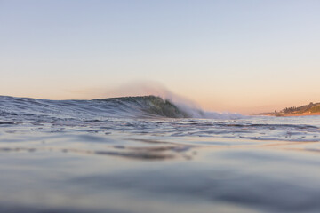 perfect wave breaking in the ocean at sunrise