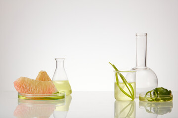 Pink pomelo slices placed on petri dish and some laboratory glassware on minimalist white...