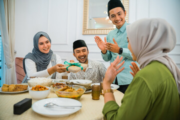 wife gives a gift to her friend before breaking the fast at home