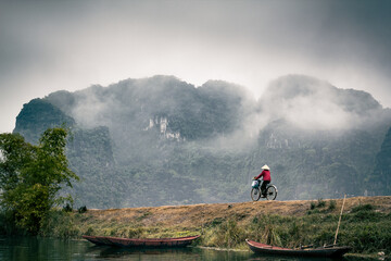 Femme à bicyclette dans la vallée brumeuse de Ninh Binh