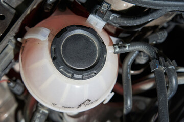 plastic expansion tank for antifreeze with a black cap and suitable pipes and tubes for automotive. View from above