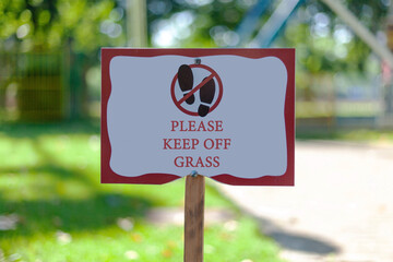 White information board "Please keep off grass"on a green lawn in a recreation park