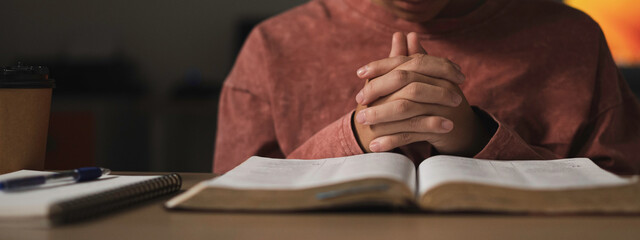 Young boy is sitting and holding hand for pray, read holy bible  and worship jesus christ in the morning at the church. pray concept christian,
