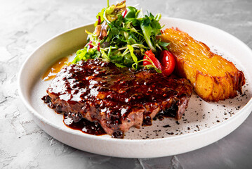 Grilled Ribeye Steak on plate with Potato gratin and salad