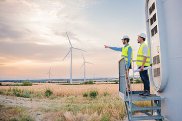 Two wind mill engineers or technicians planning a construction indicating where the new turbine...