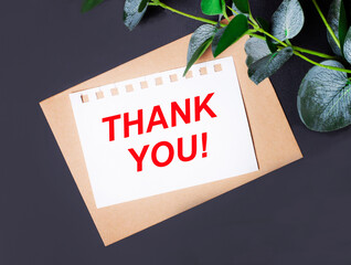 Eucalyptus leaves, an envelope and a white card with the text THANK YOU on a dark background. Flat...