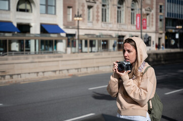 Young tourist girl in the American city of Chicago taking photos with an old classic reel photo...