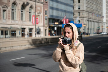 Young tourist girl in the American city of Chicago taking photos with an old classic reel photo...
