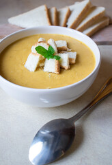 Pea soup in a white plate with crackers. lunch. Pieces of bread lie on a wooden board