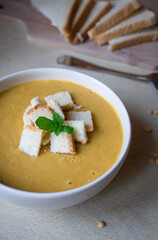 Pea soup in a white plate with crackers. lunch. Pieces of bread lie on a wooden board