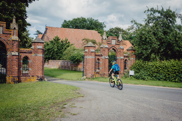 Junge fährt mit seinem Rad durch das Tor eines alten Rittergutes in Niedersachsen, Deutschland
