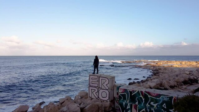 Drone shot view of a girl standing on the edge of part of abandoned Jerma Palace Hotel in Malta
