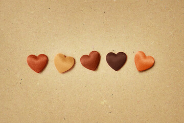 Hearts in skin colors on recycled paper background - Stop racism concept