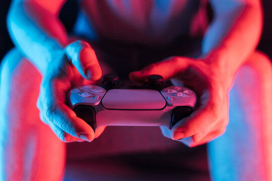 Man hands with game controller in neon light, front view